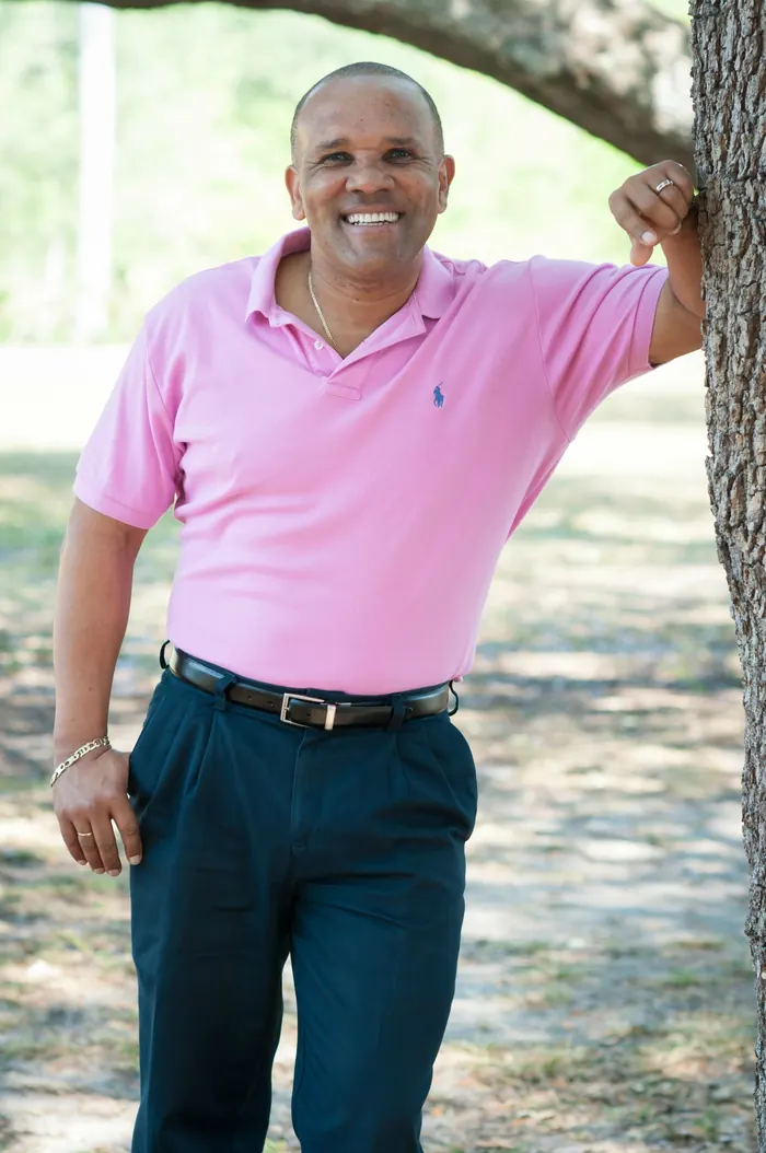 Kingsley Grant leaning against a tree outdoors, smiling